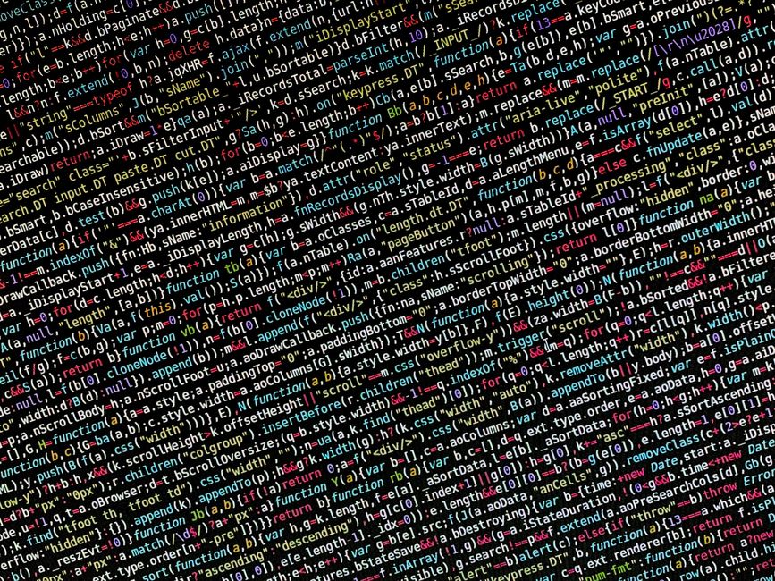 A close-up view of a laptop displaying lines of code on its screen, positioned on a wooden table. Next to the laptop, there is a coffee mug with a beige background and black text reading 'This coffee 